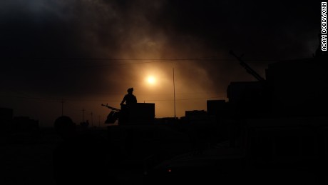 An Iraqi soldier stands guard on the outskirts of Qayyarah, under apocalyptic skies filled with smoke.