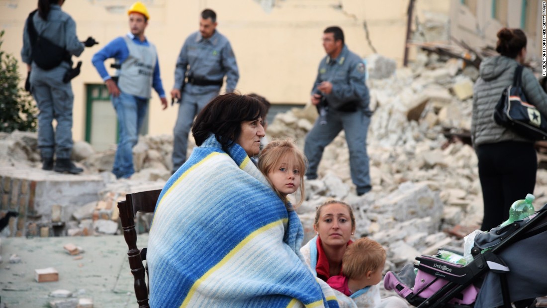 Survivors sit among the rubble of a house in Amatrice on August 24.