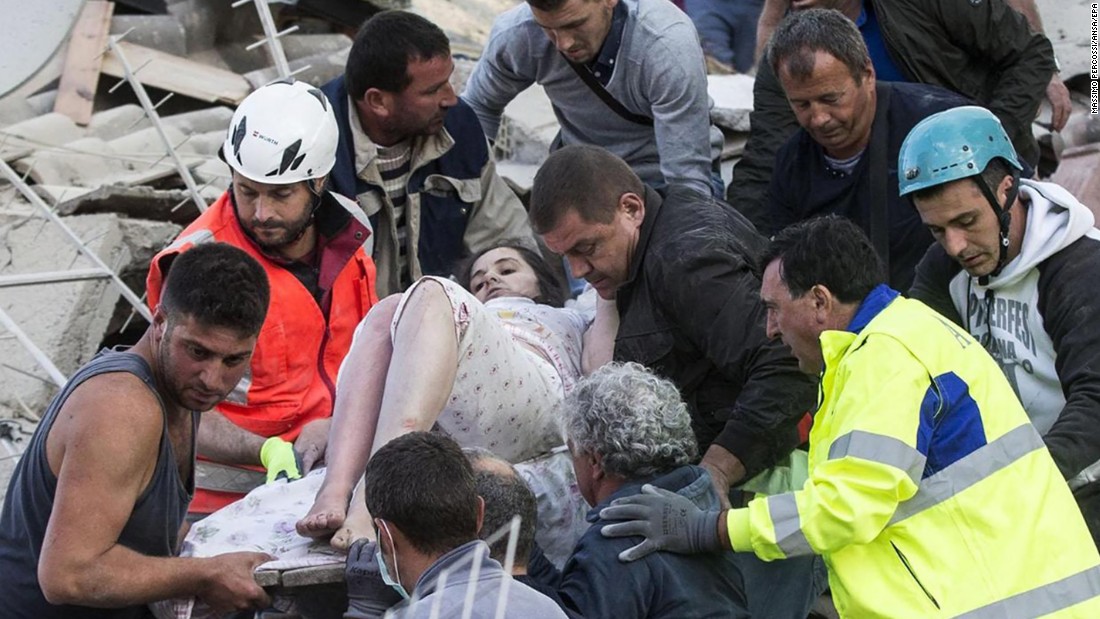 Rescuers help a woman from the rubble in Amatrice on August 24.