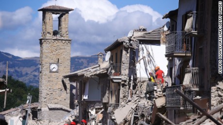 Firemen and rescuers inspect damaged buildings in Amatrice.