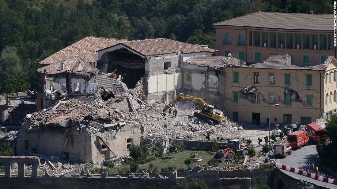 Rescue and emergency service personnel use an excavator to search for victims under the remains of a building in Amatrice on August 25.