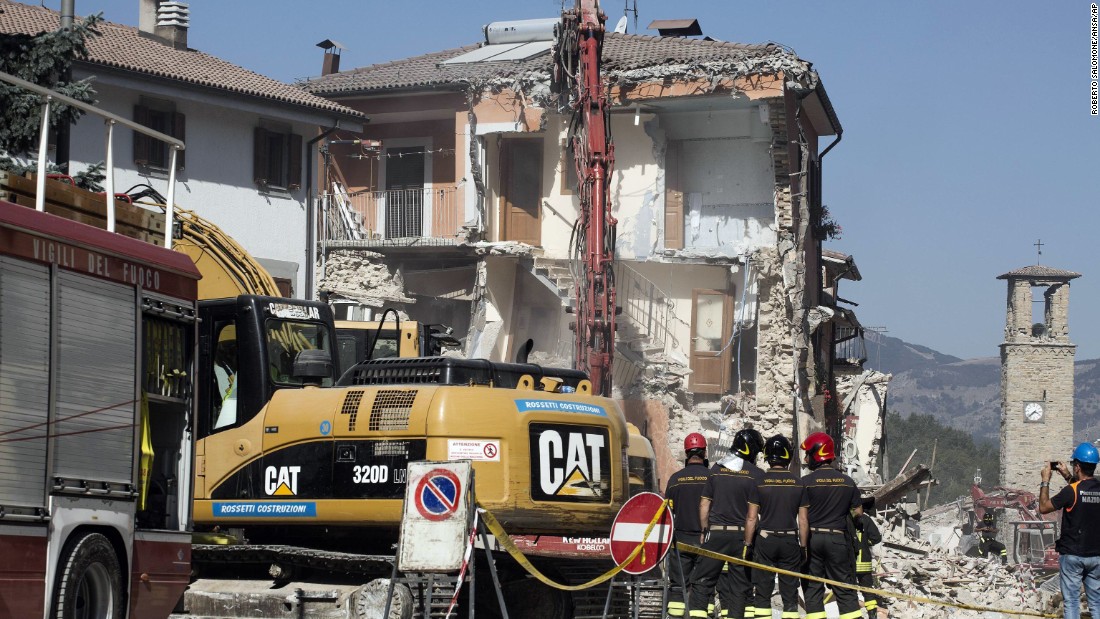 Firefighters stand by an excavator in Amatrice, Italy,on August 28, as dangerously damaged buildings and overhanging ledges are pulled down.  