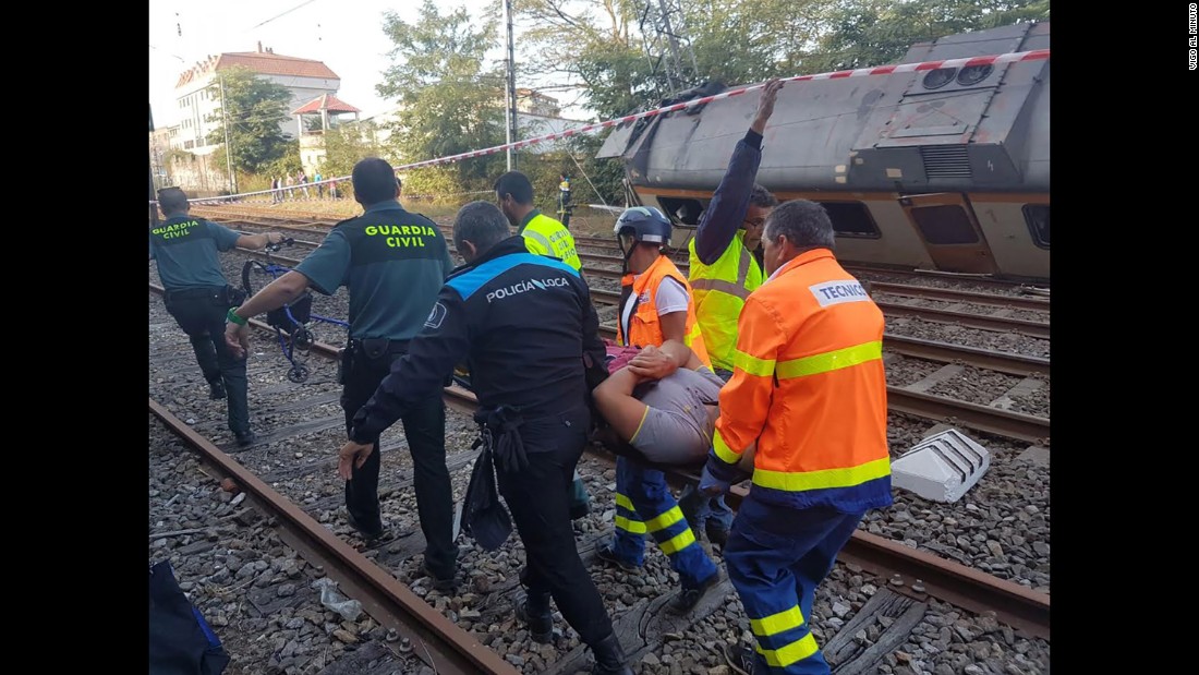 Rescuers carry an injured passenger away from the wreckage. 