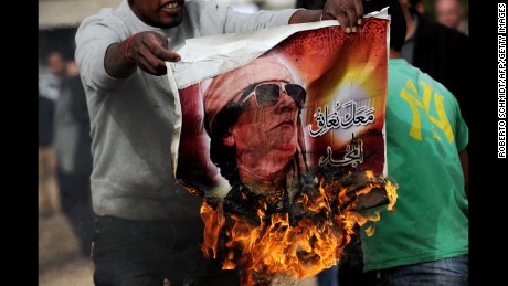 A man holds a burning poster of Moammar Gadhafi in Benghazi in March 2011.