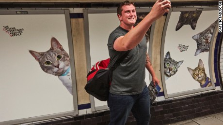 Amused commuter takes quick selfie in front of posters 