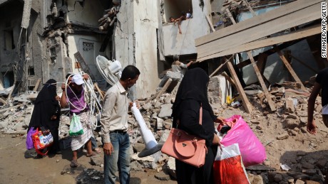 Yemenis carry belongings they recovered from the rubble of buildings destroyed during Saudi-led air strikes in 2016