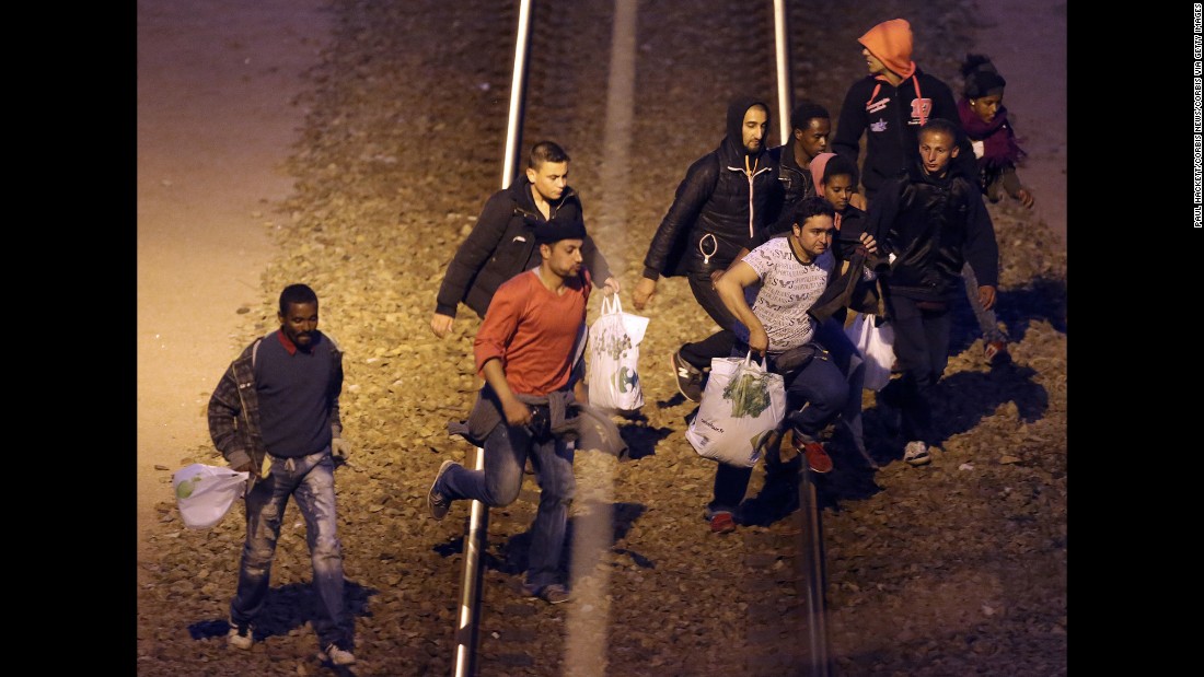Migrants walk along the railway track leading to the Eurotunnel in Calais in August 2015. Migrants attempt to enter the UK illegally by stowing away on trucks, ferries, cars or trains.