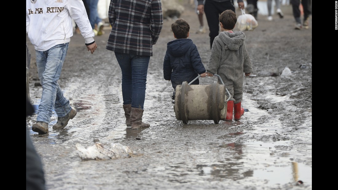 Two young boys walk in the mud inside &quot;The Jungle&quot; in December 2015.