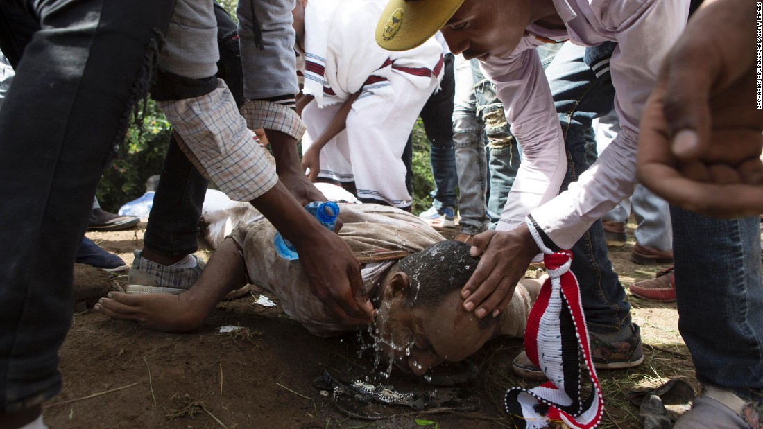 People help a man wash his eyes after police used teargas on festival participants.