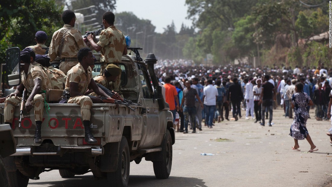 Oromo regional police officers wait in a pickup near a crowd of festival attendees.