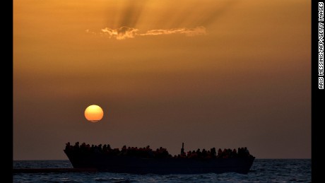 Migrants wait to be rescued as they drift at sunset in the Mediterranean Sea.