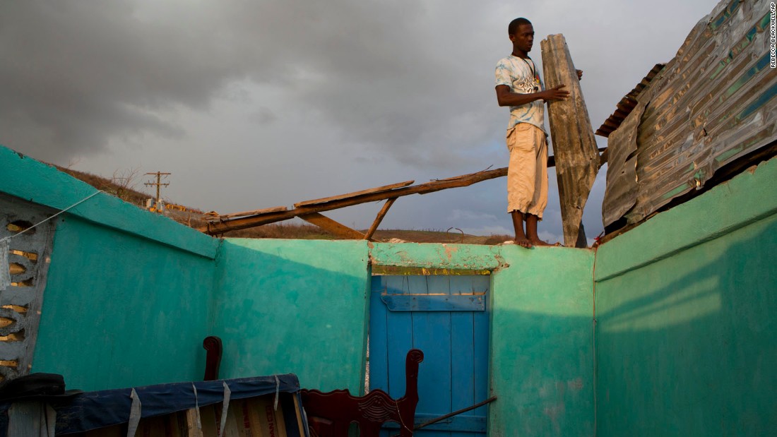 A man uses salvaged material to build a makeshift roof for his damaged house in Port-a-Piment on October 10.