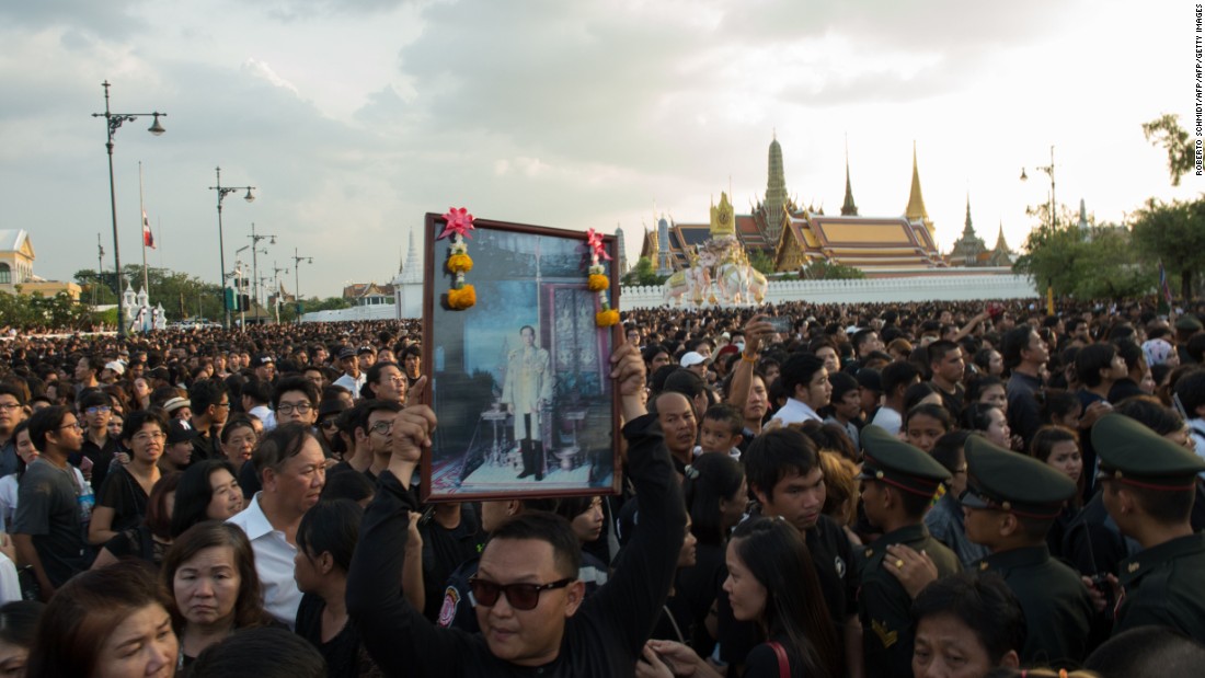 A Thai man carries high an image of Thailand&#39;s King Bhumibol Adulyadej as a large crowd floods the streets leading to the Royal Palace on October 14, 2016.