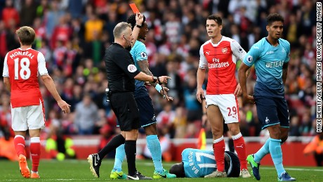 Referee Jonanthan Moss (L) shows Granit Xhaka a red card after his clumsy challenge.