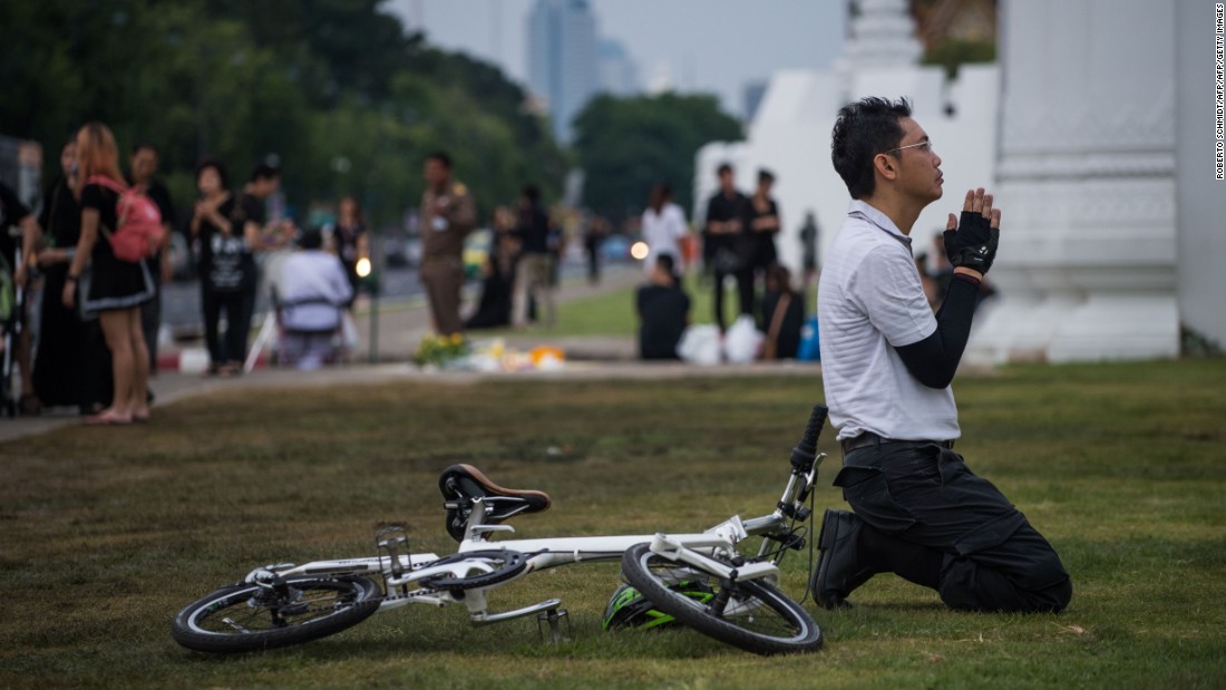 A Thai cyclist prays in front of the Grand Palace in Bangkok on October 16, 2016. Thousands of Thai men and women gather daily in the vicinity of the palace to pray for the late Thai King Bhumibol Adulyadej after his death Thursday.