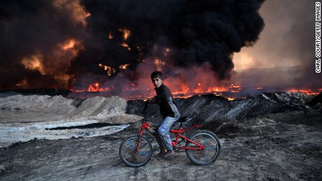 A boy pauses on his bike as he passes an oil field that was set on fire by retreating ISIS fighters ahead of the Mosul offensive, on October 21 in Qayyara.