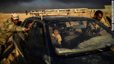 An Iraqi forces member helps a man push a car as they arrive at a refugee camp on October 22, in the town of Qayyara.