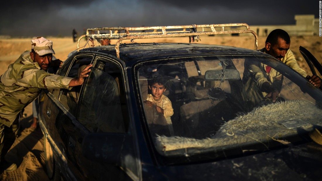 An Iraqi forces member helps a man push a car as they arrive at a refugee camp in Qayyara on October 22.