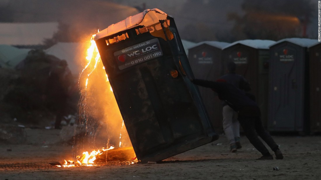 A migrant sets fire to a portable toilet inside the camp on Monday, October 24.