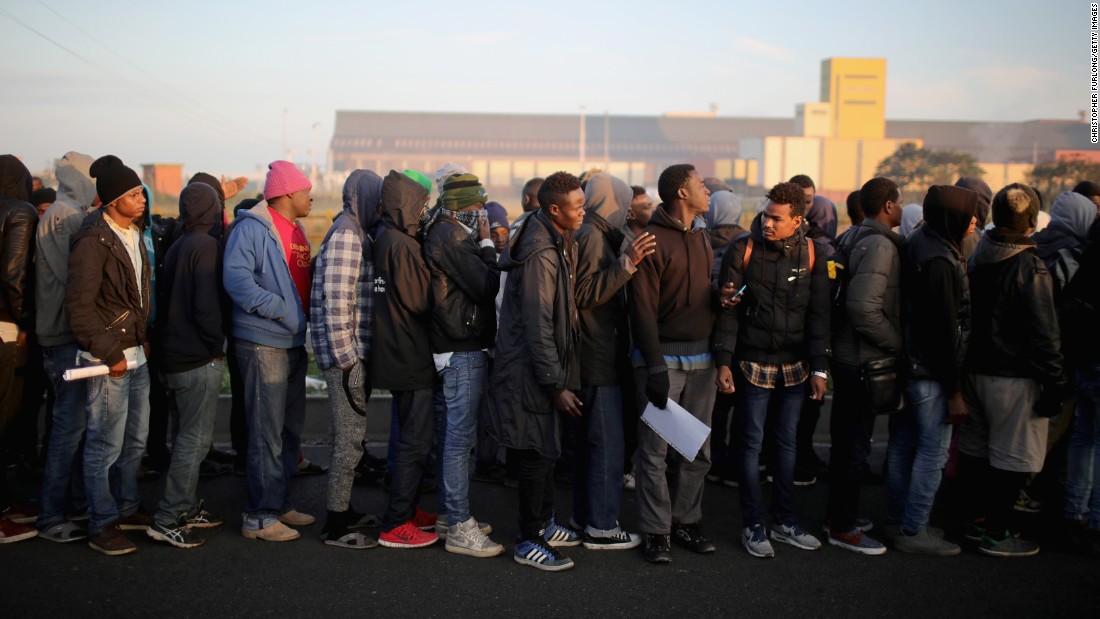 Sudanese migrants wait in line to board buses that will take them to relocation centers across France.