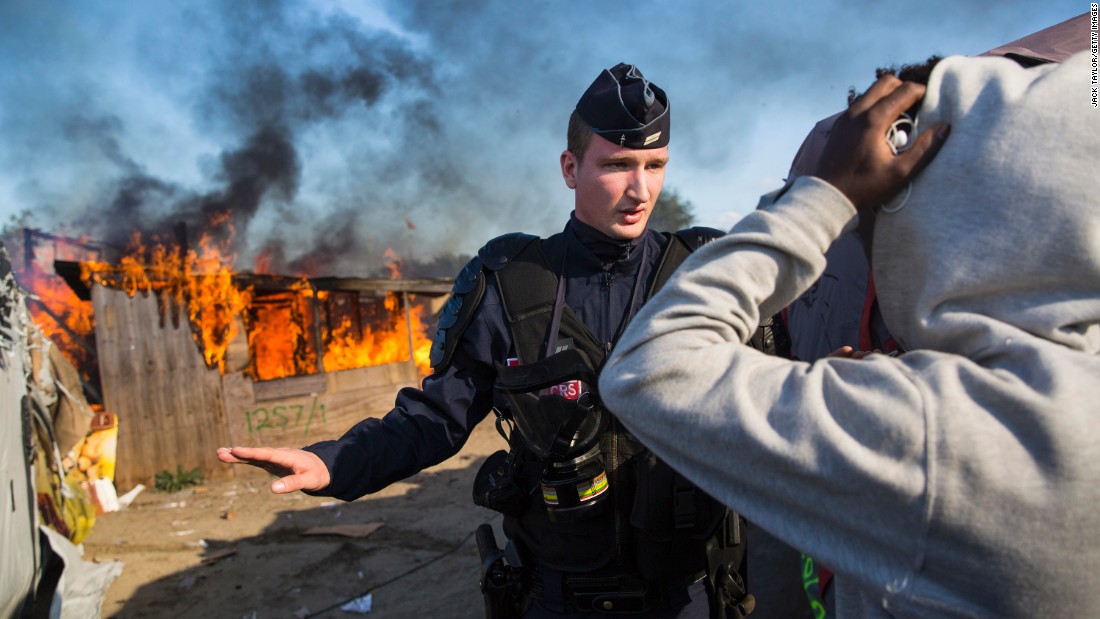 French authorities stand guard after migrants set fire to a shelter during the dismantling of the Calais &quot;Jungle&quot; camp on October 25.