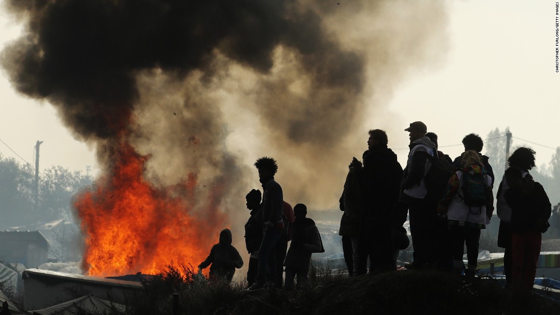 Remaining migrants watch fires burn across the Jungle on October 26. Migrants set fire to structures along the camp&#39;s main street.