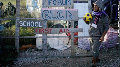 Migrants wait outside the Calais Jungle school house after they were allowed by police back inside to shelter for the night on October 28, 2016 in Calais, France.