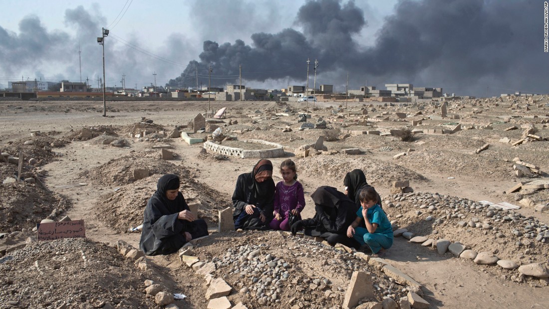 Women and children grieve over the grave of a family member at a Qayyara cemetery damaged by ISIS on October 27.