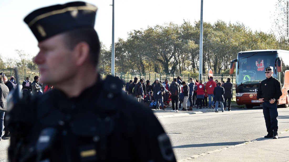 French authorities stand by as migrant minors board a bus to relocation centers on October 28. Authorities began work on Monday to clear the infamous migrant camp known as the Calais &quot;Jungle&quot; in northern France.