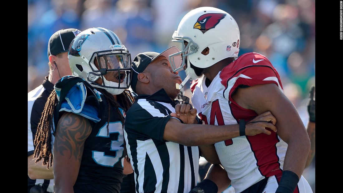 An official stands between Carolina&#39;s Tre Boston, left, and Arizona&#39;s Jermaine Gresham during an NFL game in Charlotte, North Carolina, on Sunday, October 30.