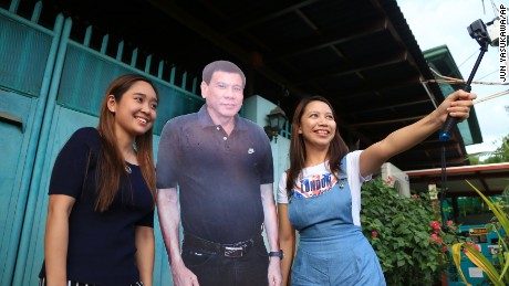 Visitors pose with a life-size picture of  Philippine President Rodrigo Duterte, in front of his house in Davao on Oct.22, 2016.( The Yomiuri Shimbun via AP Images )