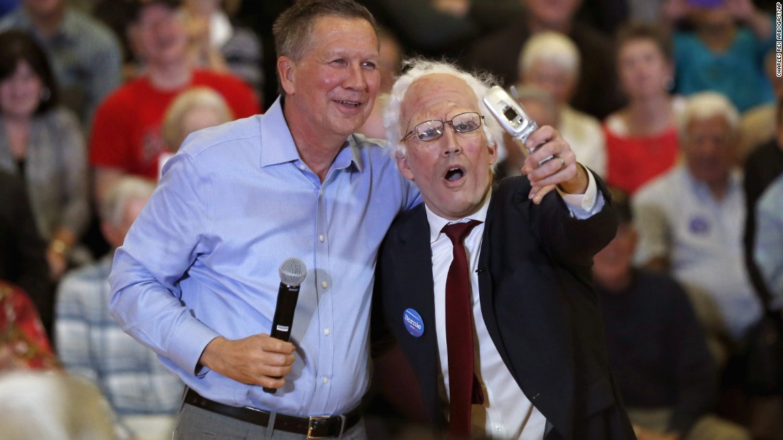 Ohio Gov. John Kasich, one of the Republican presidential candidates, poses with a Sanders impersonator at the end of a town-hall meeting in Palatine, Illinois, on March 9, 2016. 