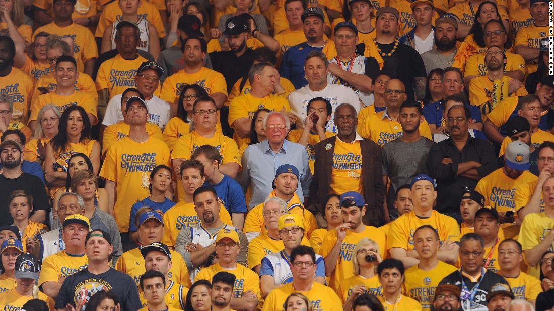 Sanders, at center in the light-blue shirt, watches a playoff basketball game in Oakland, California, on May 30, 2016. The candidate, campaigning for the state&#39;s primary, saw the Golden State Warriors win Game 7 of the NBA&#39;s Western Conference Finals.