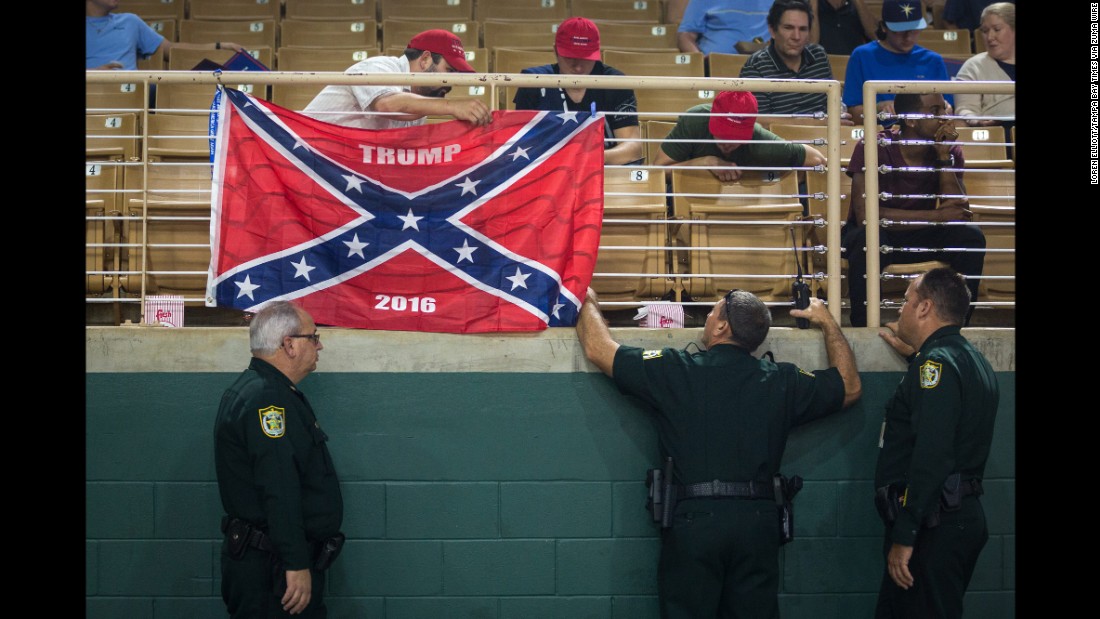 Law enforcement officers make Trump supporters remove a Confederate flag display at a Trump rally in Kissimmee, Florida, on August 11, 2016.