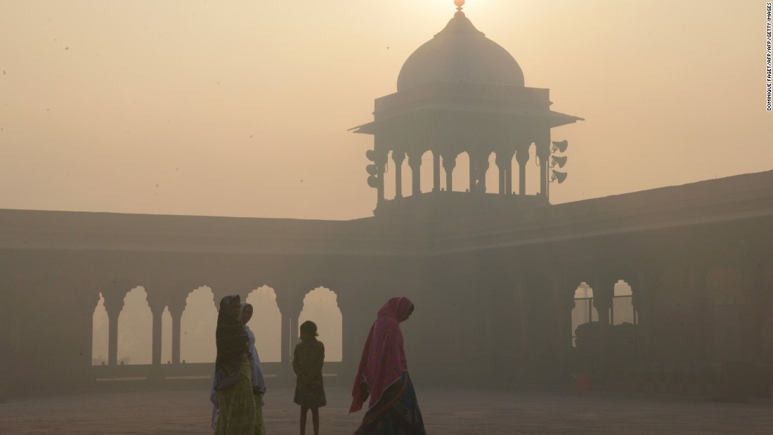 Indian women walk as smog envelops the Jama Masjid Mosque in the old quarters of New Delhi on November 3.