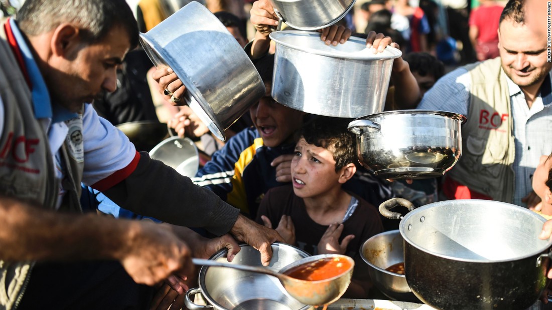 People line up to receive food at a refugee camp in the Khazir region on November 5. Thousands are taking refuge in camps set up for internally displaced people.