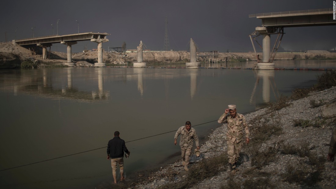 Iraqi soldiers pass near a bridge destroyed in an airstrike in Qayyara on November 5.