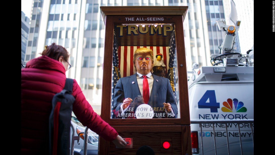 A tourist takes her &quot;misfortune&quot; slip from The All-Seeing Trump, a machine set up across the street from the New York Hilton Midtown Manhattan Hotel.