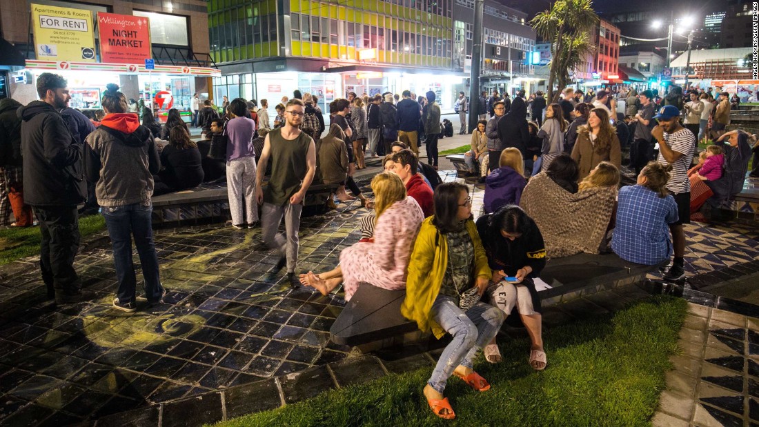 People wait in Te Aro Park after being evacuated from nearby buildings.
