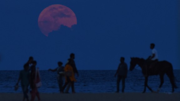 A man rides a horse past people watching the supermoon in Chennai, India, on November 14.
