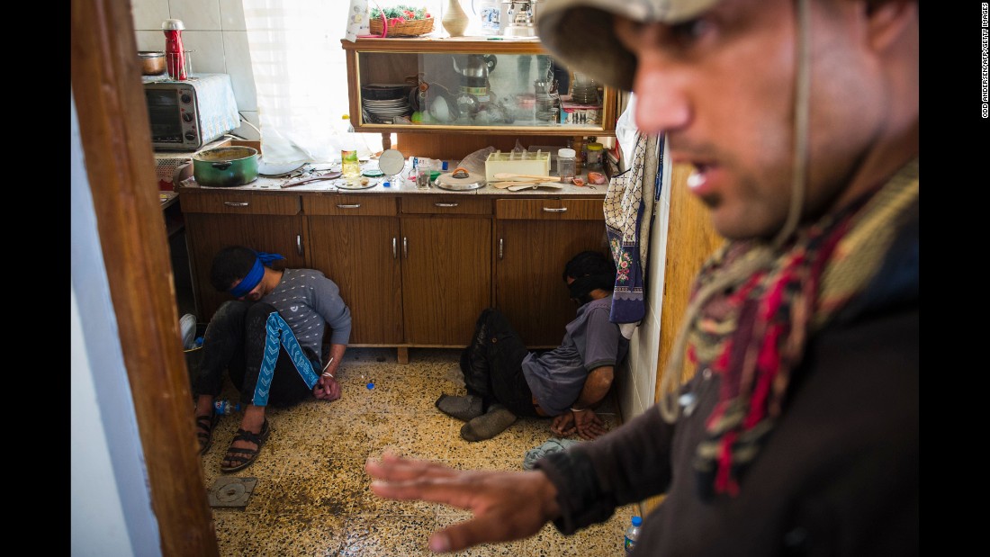 A member of Iraq&#39;s special forces guards two suspected ISIS fighters found hiding in a house in Mosul on November 11.