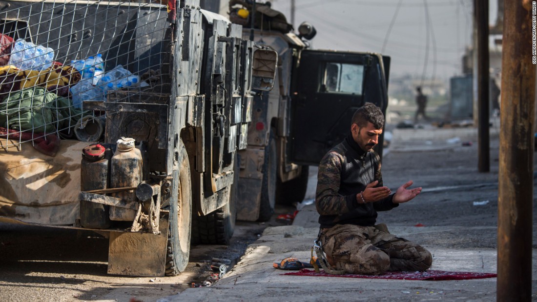 An Iraqi special forces soldier prays next to a Humvee before troops pushed toward Mosul&#39;s Karkukli neighborhood on November 13.