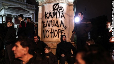 Protesters stand in front of graffiti that reads &quot;No Hope&quot; on Tuesday in Athens.