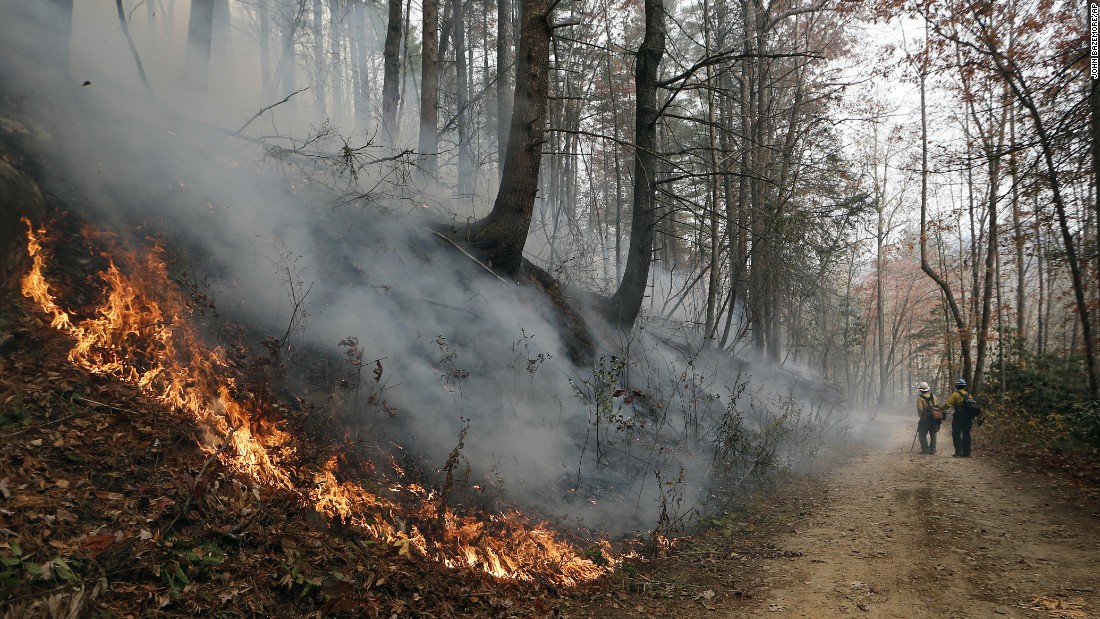 Firefighters walk down a dirt road as a wildfire burns a hillside in Clayton, Georgia, on Tuesday, November 15. 