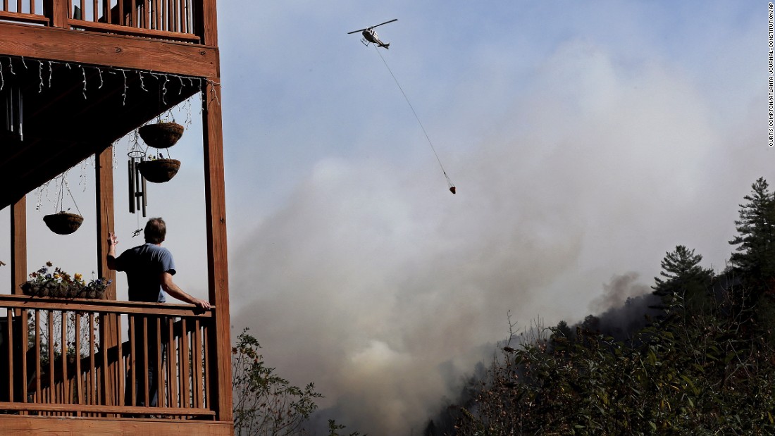 Eric Willey looks on from the porch of his home as a helicopter fights a wildfire in Tate City, Georgia, on Wednesday, November 16. 