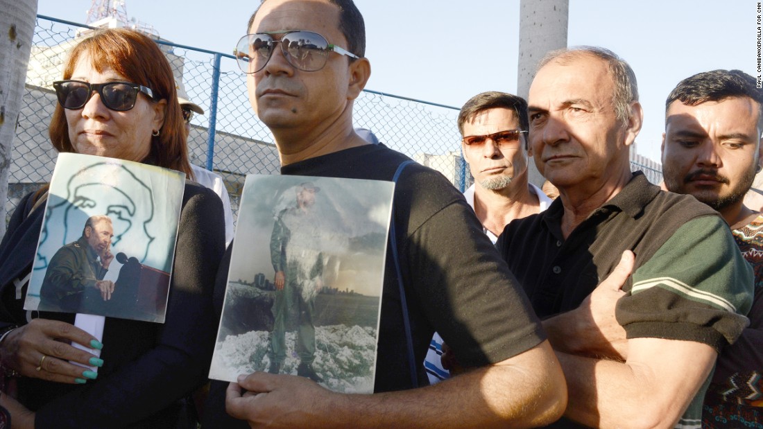 Cubans hold photos of Castro as they wait to pay their respects at Revolution Square on November 28.