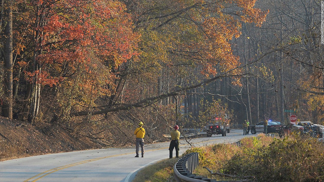 Fire crews bring down a dead tree along Highway 9 near the community of Bat Cave, North Carolina, on Friday, November 18.