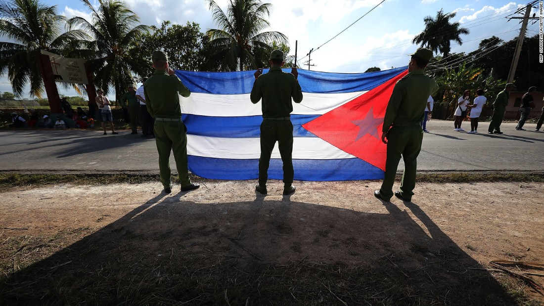 Ministry of Interior troops hold a Cuban flag as they wait for the military caravan transporting Castro&#39;s remains on November 30.