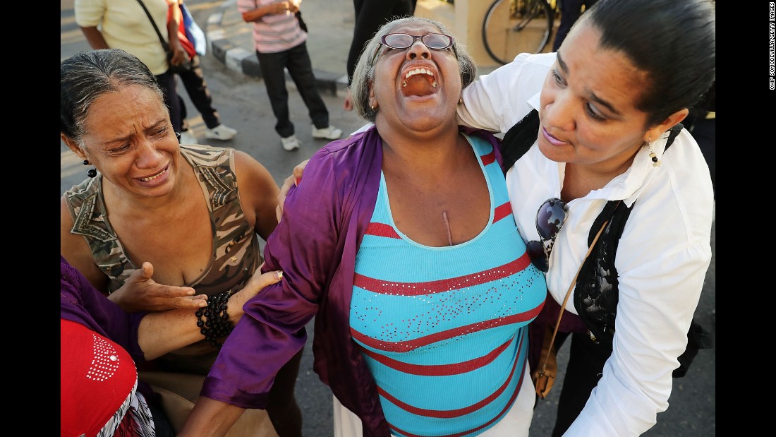 Women comfort one another after watching Castro&#39;s remains pass by in Havana on November 30.