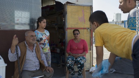 Raja Paulous, center, talks to neighbors at the entrance to her refugee camp grocery.